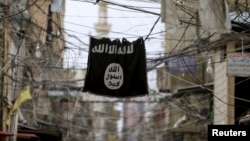 FILE - An Islamic State flag hangs amid electric wires, Jan. 19, 2016. 