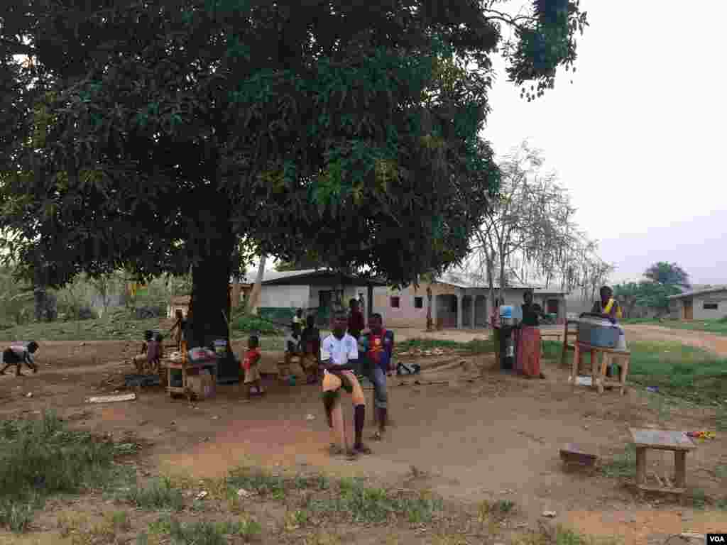 People sitting under a mango tree at dusk in a small community, one the worst affected communities of Ganta, Liberia, April 7, 2014. (Benno Muchler/VOA)