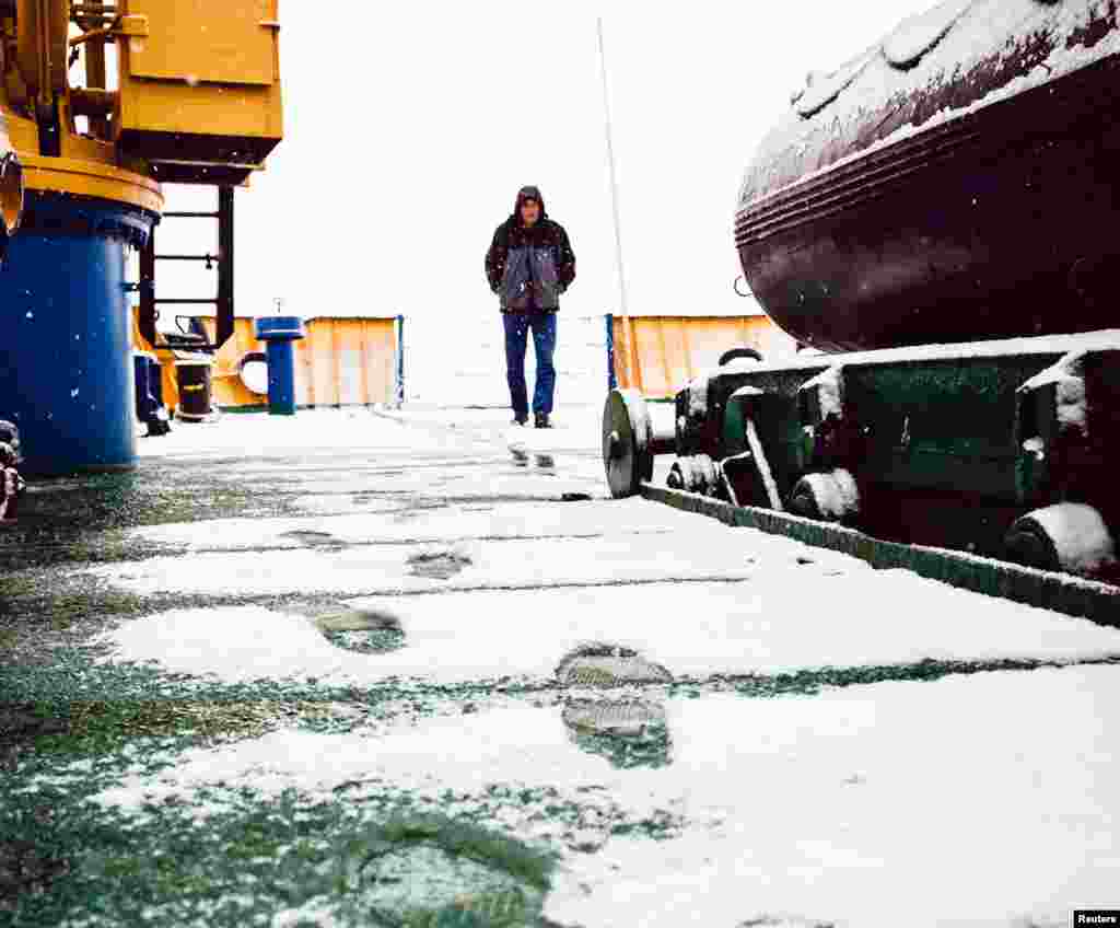 A crew member of the MV Akademik Shokalskiy walks on the snow-covered aft deck of the stranded ship in the Antarctic, Dec. 29, 2013.