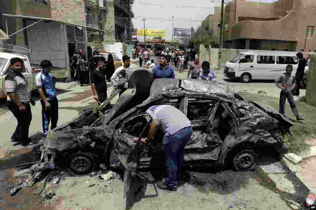 People look at damage from a car bomb, Baghdad, May 30, 2013.