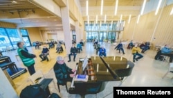 Un pianiste divertit des résidents âgés qui attendent de recevoir un vaccin contre le coronavirus (COVID-19) à l'église de Rotnes, à Nittedal, Norvège, le 21 janvier 2021.