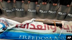 Tentara anti-huru-hara berjaga-jaga di depan spanduk rusak milik Partai Kebebasan dan Keadilan yang berafiliasi dengan Ikhwanul Muslimin, di Kairo. (Foto: Dok)
