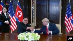 Pemimpin Korea Utara Kim Jong Un bersalaman dengan Presiden Donald Trump disaksikan oleh adik Kim Jong Un, Kim Yo Jong, dalam KTT di Singapura, 12 Juni 2018.