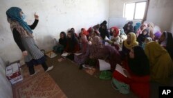 FILE - Afghan internally displaced school girls and women study at a class near their temporary homes on the outskirts of Kabul, Afghanistan, Oct. 30, 2017.