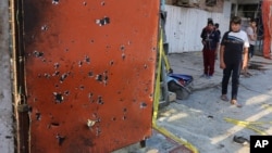 People inspect the scene after an explosion hit a busy commercial area in Baghdad, Iraq Monday, July 13, 2015. 