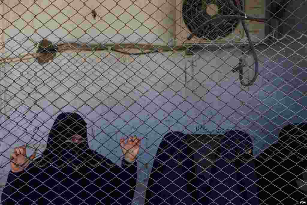 A detainee in Roj Camp watches shoppers in the market area of the detention facility in Northeast Syria, on Oct. 13, 2024. (Diego Baravelli/VOA)