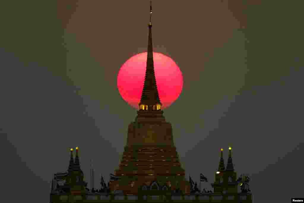 ព្រះអាទិត្យលិចនៅខាងក្រោយប្រាសាទ Wat Saket ឬភ្នំមាសនៅក្នុងទីក្រុងបាងកកប្រទេសថៃកាលពីថ្ងៃទី១១ ខែមីនា ឆ្នាំ២០១៩។