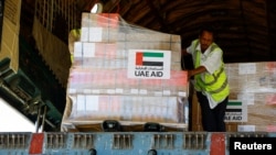 Workers unload aid from World Health Organization (WHO) and UAE-AID from United Arab Emirates at the Port Sudan International Airport, Port Sudan