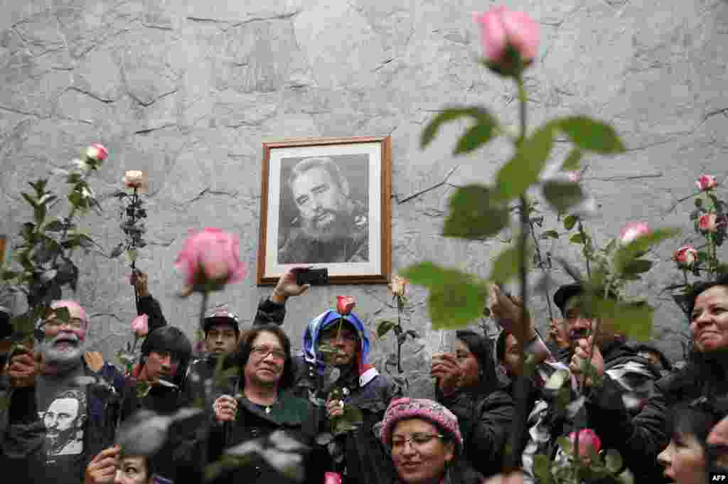 Warga membawa bunga di depan potret mendiang pemimpin revolusi Kuba Fidel Castro di Kedutaan Kuba di Bogota, Kolombia.