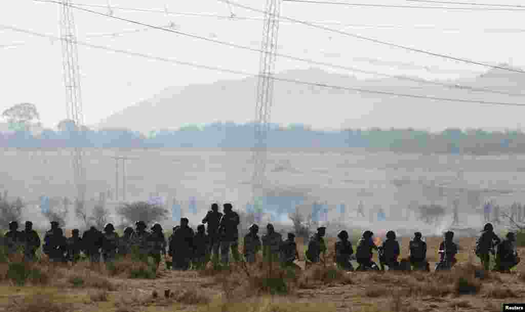 Policemen fire at striking miners outside a South African mine in Rustenburg, August 16, 2012.