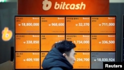 FILE - A man walks past an electric board showing exchange rates of various cryptocurrencies including Bitcoin (top-L) at a cryptocurrencies exchange in Seoul, South Korea, Dec. 13, 2017. (REUTERS/Kim Hong-Ji )