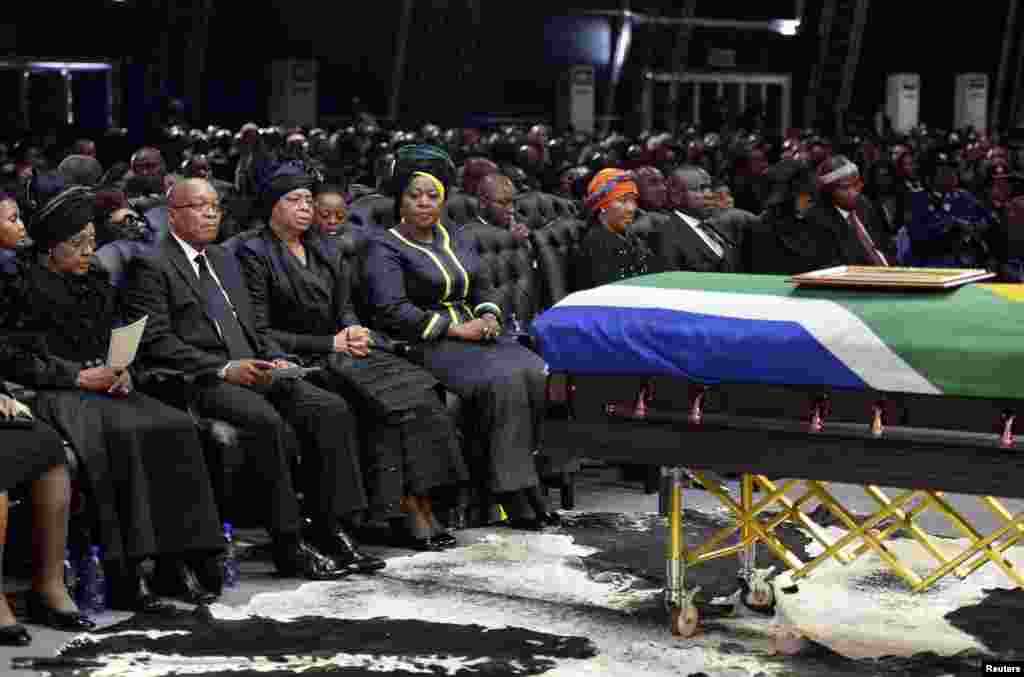 Presiden Afrika Selatan Jacob Zuma (kedua kiri), mantan istri mantan presiden Afrika Selatan Nelson Mandela, Winnie Mandela (kiri), dan janda Mandela, Graca Machel (ketiga kiri), duduk dekat peti mati Mandela pada upacara pemakaman di Qunu, Afrika Selatan, 15 Desember 2013.