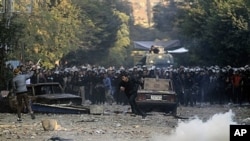 A protester runs for cover during clashes with Egyptian riot police near Tahrir Square in Cairo, Egypt, Monday, Nov. 21, 2011. Security forces fired tear gas and clashed Monday with several thousand protesters in Cairo's Tahrir Square in the third straigh