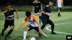 In this July 15, 2018, photo, Wild Boars soccer team, in black, play a local team during a Mae Sai league match in Mae Sai district in Chiang Rai province, northern Thailand. 