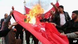 Protesters burn a Turkish flag during a demonstration calling for the withdrawal of Turkish troops from northern Iraq, in Basra, Iraq, Dec. 18, 2015.