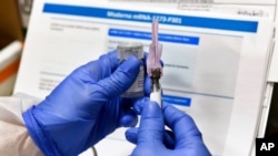 FILE - Nurse Kathe Olmstead prepares a shot that is part of a possible COVID-19 vaccine, developed by the National Institutes of Health and Moderna Inc., in Binghamton, New York, July 27, 2020.