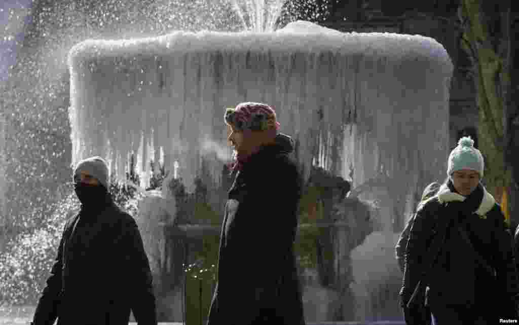 People walk past the ice covered Josephine Shaw Lowell Memorial Fountain, in frigid temperatures in Bryant Park in the Manhattan borough of New York City. Schools in Chicago, Boston and other large cities closed on Thursday as sub-zero temperatures and bitter winds gripped central and eastern U.S. for a third day and meteorologists warned there was little relief in sight.
