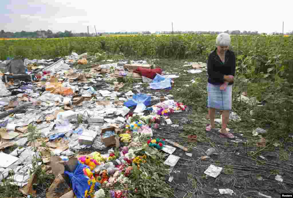A resident stands near flowers and mementos placed at the crash site of Malaysia Airlines Flight MH17, near the settlement of Rozspyne in the Donetsk region, eastern Ukraine, July 19, 2014.