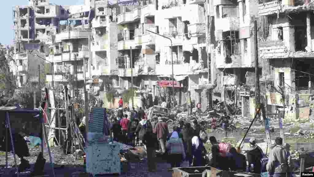 Civilians carry their belongings as they walk towards a meeting point to be evacuated from a besieged area of Homs, Feb. 9, 2014.
