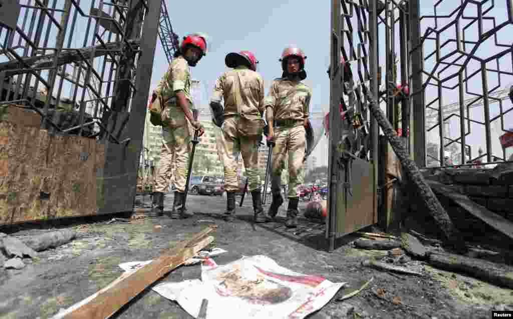 A poster of deposed Egyptian President Mohamed Morsi lies on the ground as military police stand outside the burnt Rabaa Adawiya mosque, Cairo, August 15, 2013.