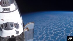 Backdropped by the blackness of space and Earth's horizon, Space Shuttle Endeavour, docked to the Pressurized Mating Adapter on the International Space Station, is featured in this photograph taken during the mission's first planned spacewalk.