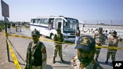 Pakistani paramilitary soldiers stand guard next to a damaged bush at the site of a bomb blast in Karachi, Pakistan, April 26, 2011