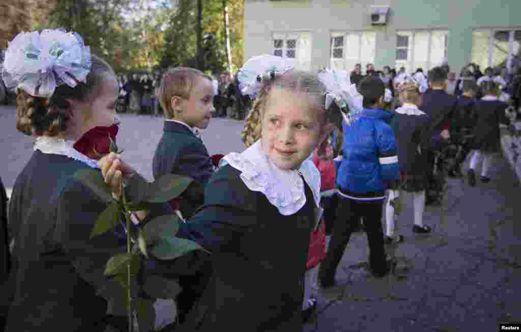 A first-grade pupil looks back at her mother while walking to a school building after a festive ceremony to mark the beginning of another academic year in Makiivka, eastern Ukraine, Oct. 1, 2014.