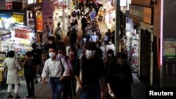 Personas con máscaras protectoras, en medio del brote de la enfermedad por coronavirus, se dirigen a un distrito comercial en Tokio, Japón, el 28 de julio, 2021.