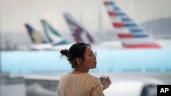 Une femme se tient debout avec son téléphone portable à l'aéroport international de Hong Kong, le lundi 12 août 2019. 