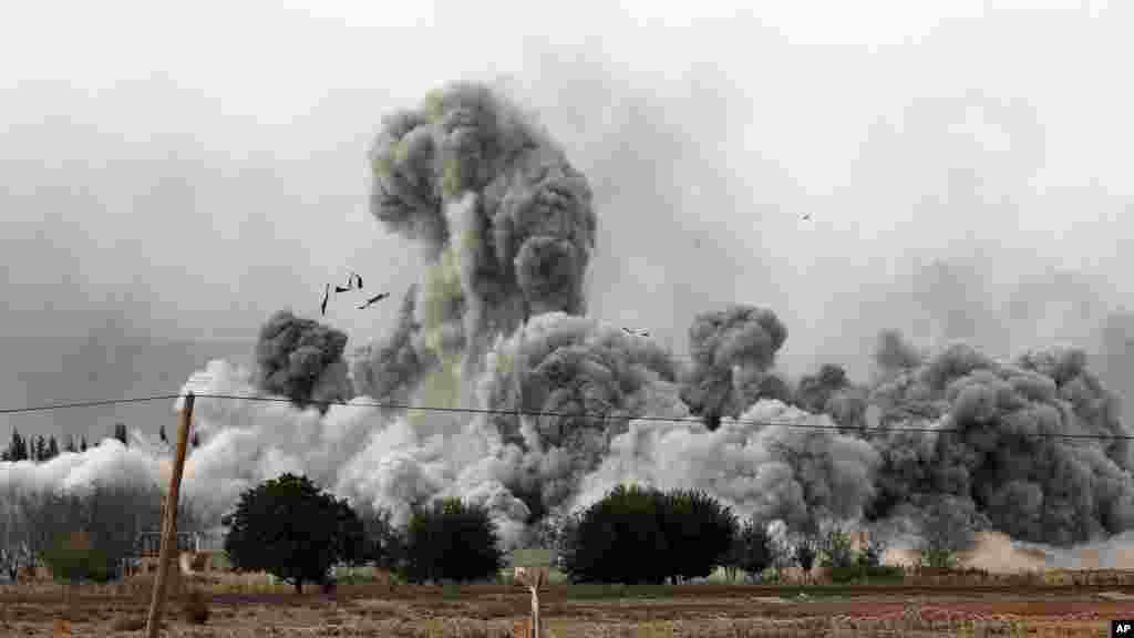 Epaisse fumée et débris s'élèvent après une frappe de la coalition menée oar les Etats-Unis à Kobani, en Syrie, dimanche le 12 ocotbre 2014. (AP Photo/Lefteris Pitarakis)