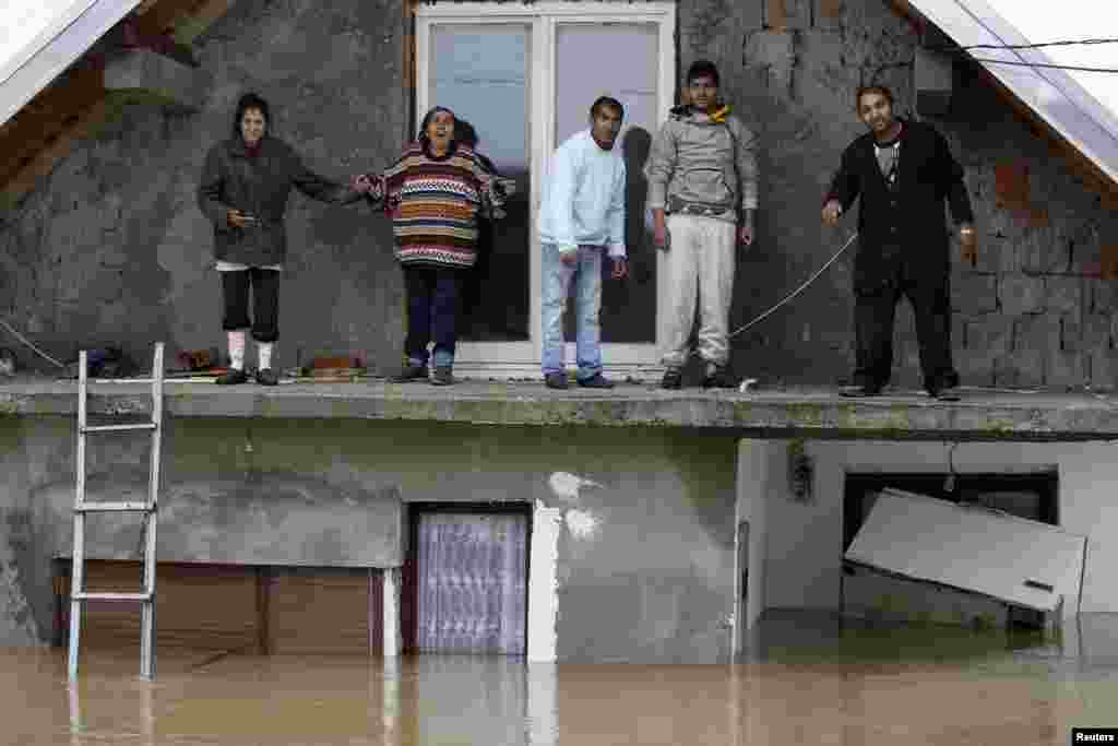 Orang-orang berdiri di teras rumah mereka yang kebanjiran menunggu untuk dievakuasi di kota Obrenovac, di sebelah timur Belgrade, Serbia. 