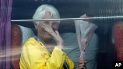 A passenger waves from a bus after she disembarked from the Westerdam, owned by Holland America Line, at the port of Sihanoukville, Cambodia, Feb. 14, 2020.