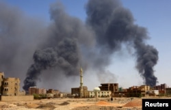 A man walks while smoke rises above buildings after aerial bombardment, during clashes between the paramilitary Rapid Support Forces and the army in Khartoum North, Sudan, May 1, 2023.
