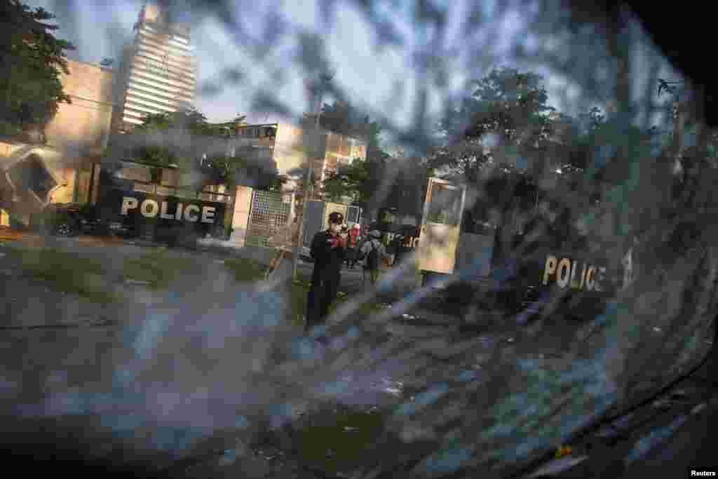 A Thai security officer is seen through a shattered windscreen of a destroyed police truck at the Thai-Japan youth stadium in central Bangkok, Thailand, Dec. 27, 2013.
