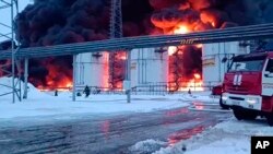 Petugas dari Kementerian Darurat Rusia menangani kebakaran di tangki minyak setelah drone menghantam Klintsy, sebuah kota di Wilayah Bryansk, Rusia, yang terletak sekitar 60 kilometer dari perbatasan Rusia-Ukraina. (Foto: via AP)