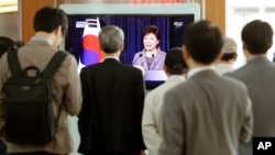 People at the Seoul Train Station watch a live television program showing South Korean President Park Geun-hye explain her decision to dismantle the Coast Guard after last month's deadly ferry incident, in Seoul, South Korea, May 19, 2014.