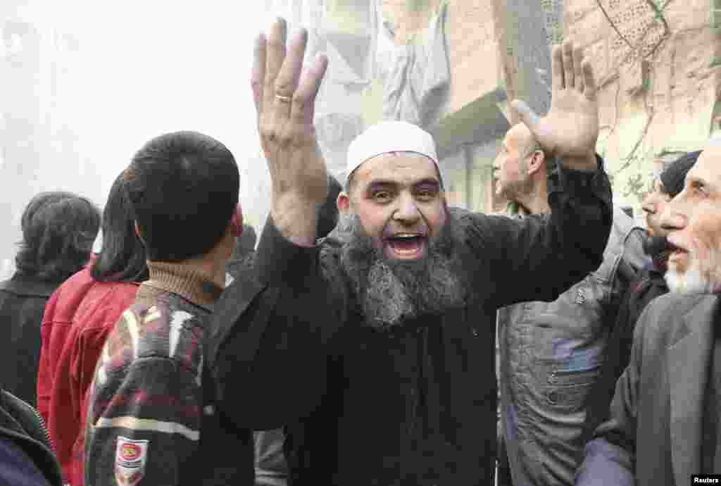 A man waves his arms at a site hit by what activists said was a barrel bomb dropped by forces loyal to President Bashar Assad in the al-Shaar district, Aleppo, Feb. 9, 2014. 
