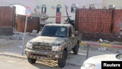 Seorang anggota pasukan keamanan yang setia kepada pemerintah Libyan yang didukung PBB mengendarai pickup di penjara Al-Hadba yang rusak saat baku tembak dengan faksi saingan di distrik Abu Salim, di Tripoli, Libya, 28 Mei 2017. (Foto: Hani Amara/Reuters)