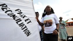 A supporter of Ivorian President Alassane Ouattara dances as she holds a banner reading in French "Peace and reconciliation" during a meeting on April 22, 2012 in Guiglo. 