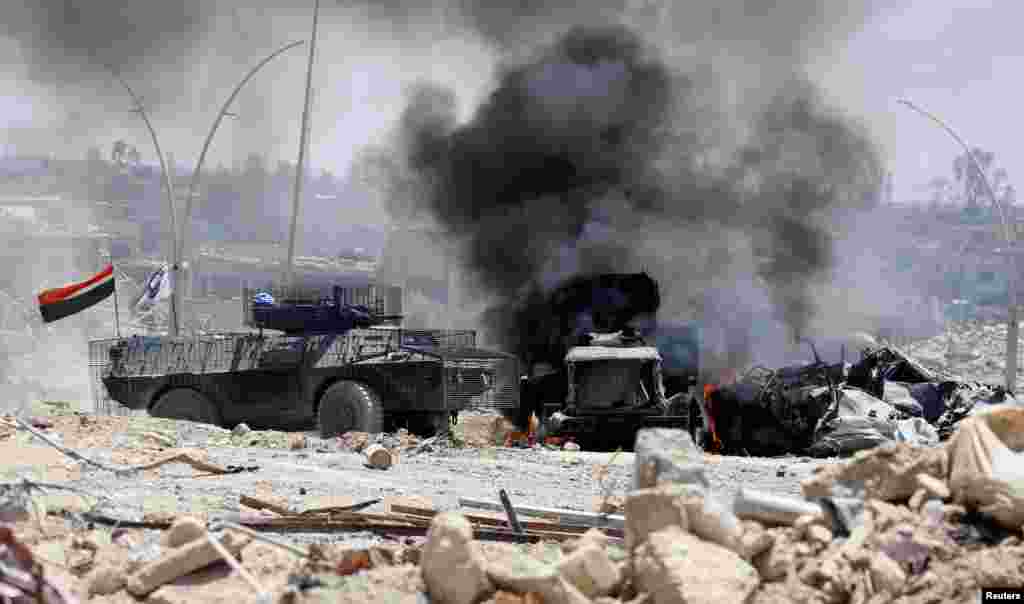 Sebuah truk militer pasukan Irak terbakar setelah terkena tembakan militan ISIS dalam pertempuran di Mosul barat.