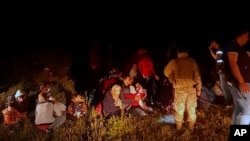 In this photo released by the Lebanese Army official website, Lebanese troops stand next to Syrian migrants who tried to go by boat to the Mediterranean island of Cyprus, April 25, 2001.