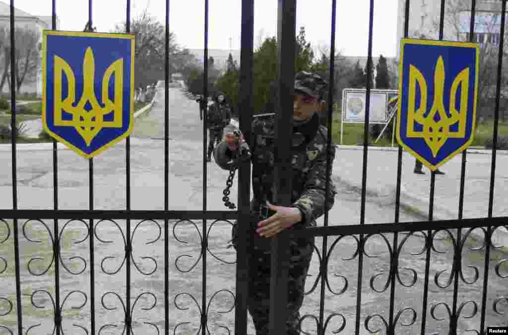 A Ukrainian soldier closes an entrance gate at the air force base in the Crimean town of Belbek, March 20, 2014.