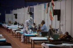 A health worker takes temperature of a patient at a makeshift COVID-19 care center in New Delhi, India, Sept. 19, 2020.
