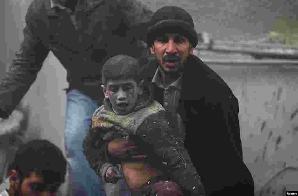 A man helps a wounded boy who survived what activists say was an airstrike by forces loyal to Syrian President Bashar al-Assad in the Duma neighborhood of Damascus.