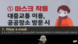 在南韓首爾東大門設計廣場，一名戴著口罩的婦女經過顯示預防冠狀病毒的屏幕。(2020年4月19日)