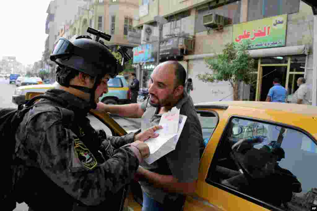 A police officer checks papers at a checkpoint in central Baghdad, Oct. 31, 2013.