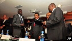 Nhail Deng Nhail, 2nd from left, the head of South Sudan's negotiating team, and lead negotiator for the rebels, Taban Deng Gai, right, sign a ceasefire agreement in front of Ethiopia's foreign minister, Tedros Adhanom.