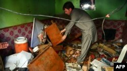 Seorang warga Pakistan memeriksa televise yang rusak di kantornya menyusul ledakan bom di Karachi (15/3).