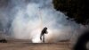 An Egyptian protester throws a tear gas canister back at riot police, not seen, during clashes near Tahrir Square, Cairo, Egypt, Sunday, Jan. 27, 2013.