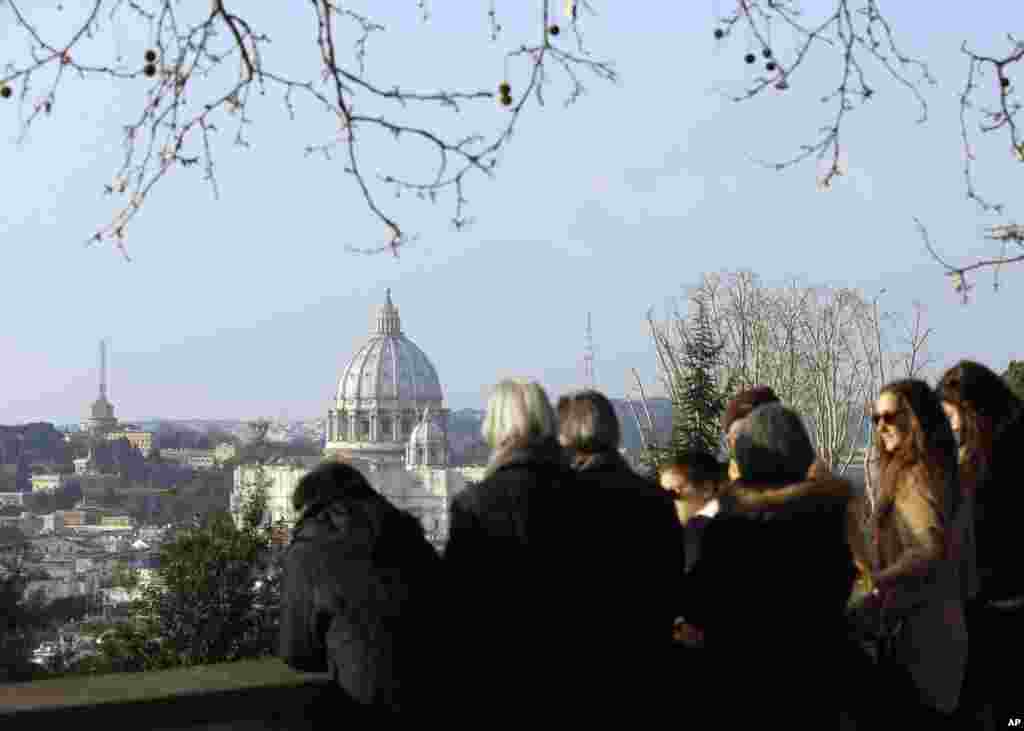 People wait in Rome to see the helicopter taking Pope Benedict to Castel Gandolfo, Feb. 28, 2013.